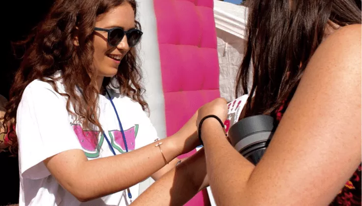 A volunteer collecting for CoppaFeel! gives someone a sticker | CoppaFeel! | Breast cancer awareness