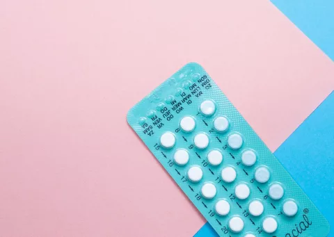 A contraceptive pill packet on a pink and blue background | CoppaFeel! | Breast cancer awareness