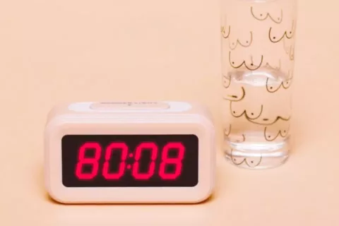 Alarm clock reading '8008' next to a glass of water illustrated with boobs | CoppaFeel! | Breast cancer info and advice