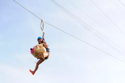 A woman wearing a CoppaFeel! boob suit on a zip line