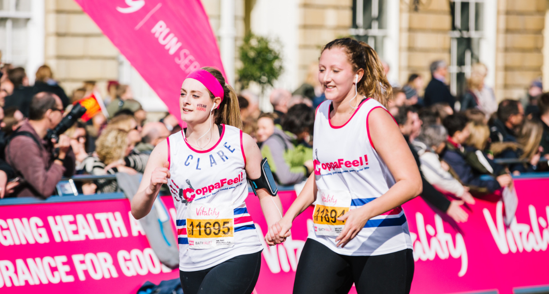 Two women wearing CoppaFeel! running vests whilst running in a marathon